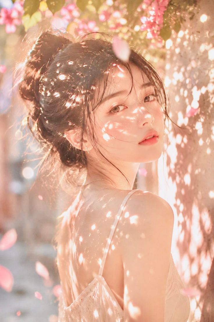 Woman with an updo in soft golden hour light with pink petals
