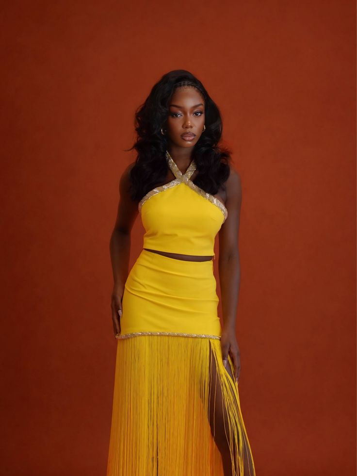 Woman in a yellow halter top and fringe skirt with a high slit