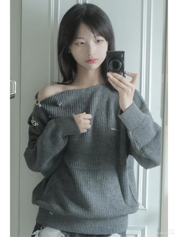 Woman in an off-shoulder sweater taking a mirror selfie
