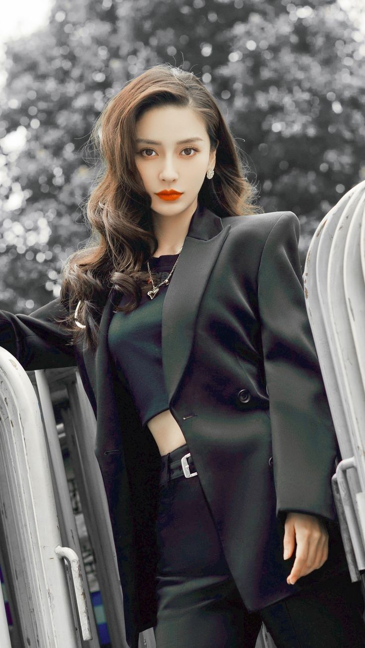 Woman with long wavy hair wearing a black blazer and crop top outdoors