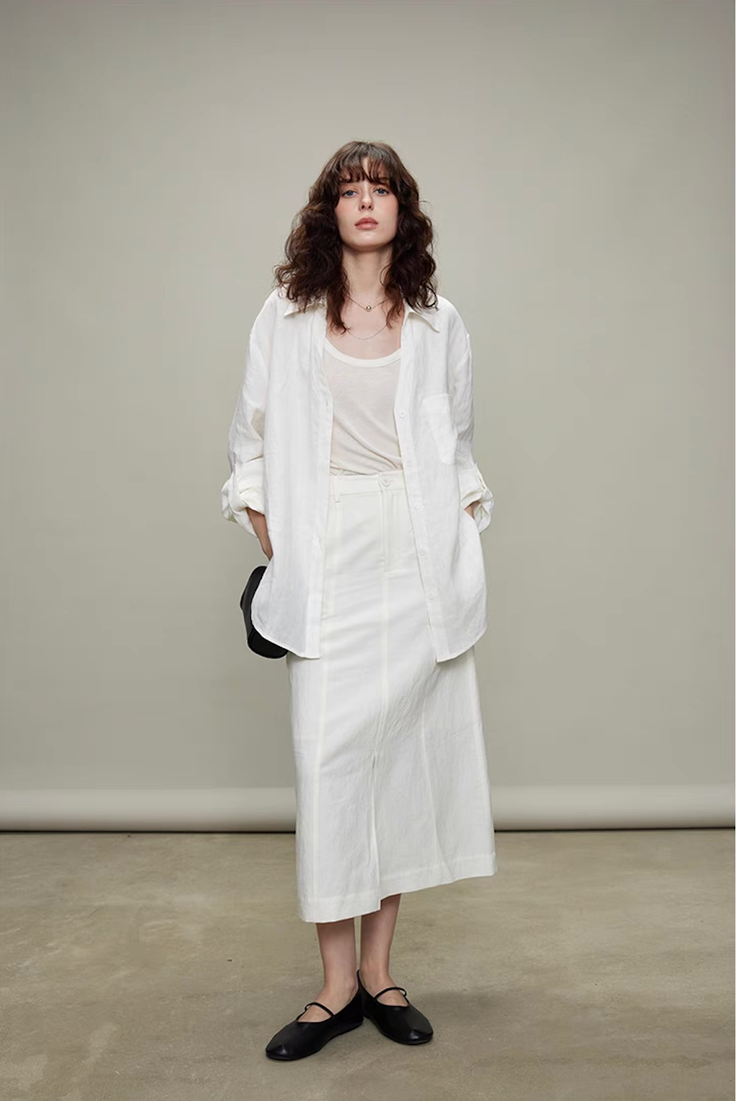 Woman in a white shirt and skirt with long wavy hair in a studio