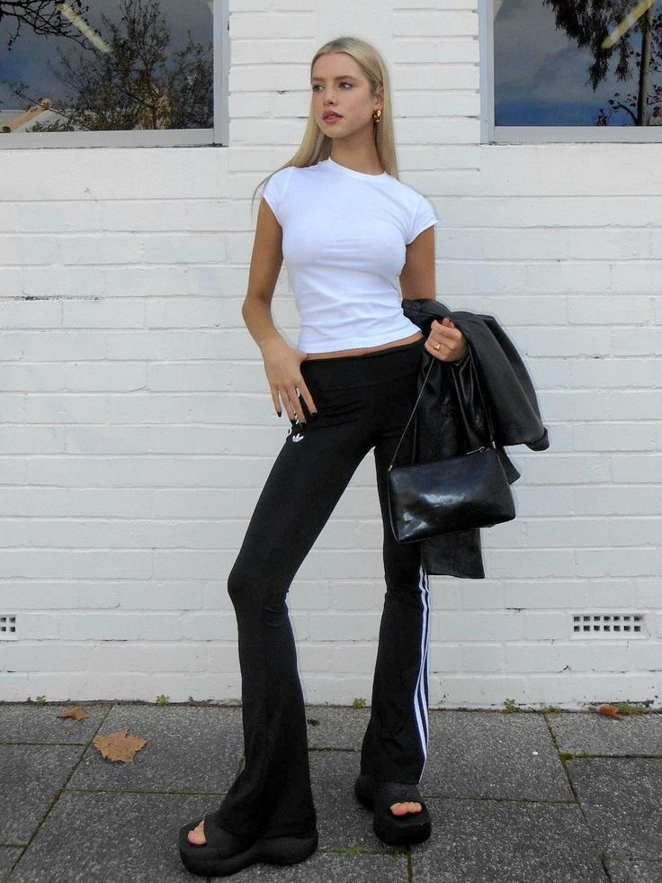 Woman with blonde hair wearing a white t-shirt and black pants outdoors