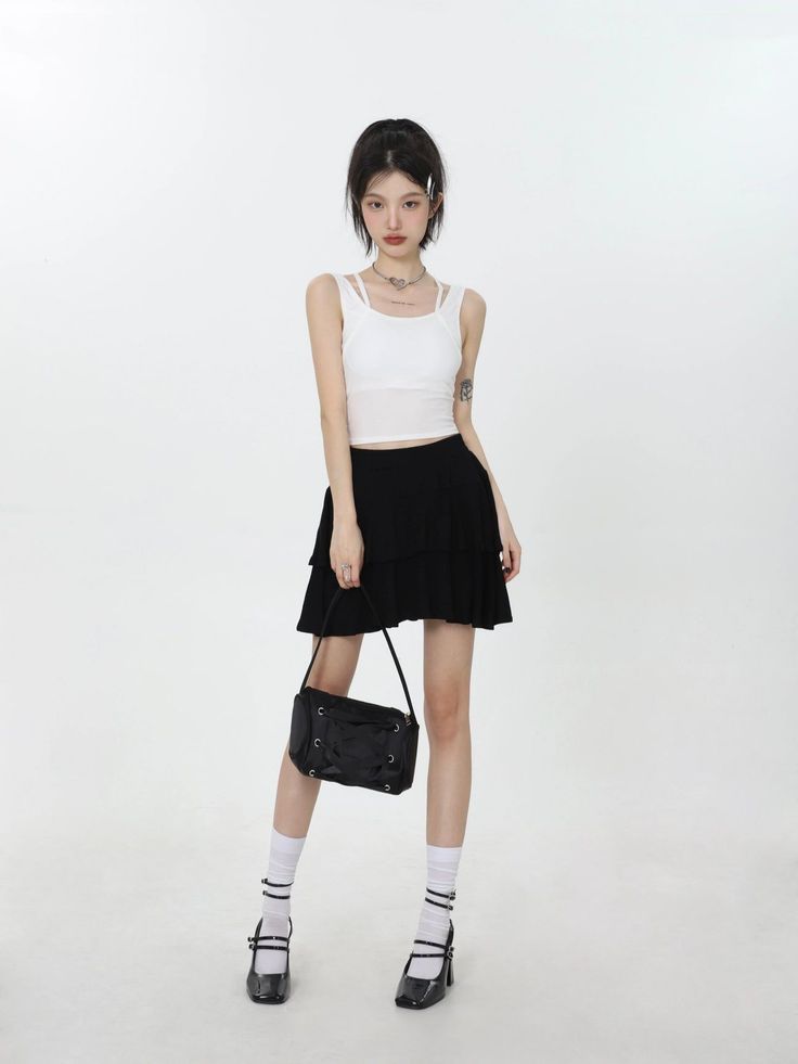 Woman in a white tank top and black mini skirt holding a shoulder bag