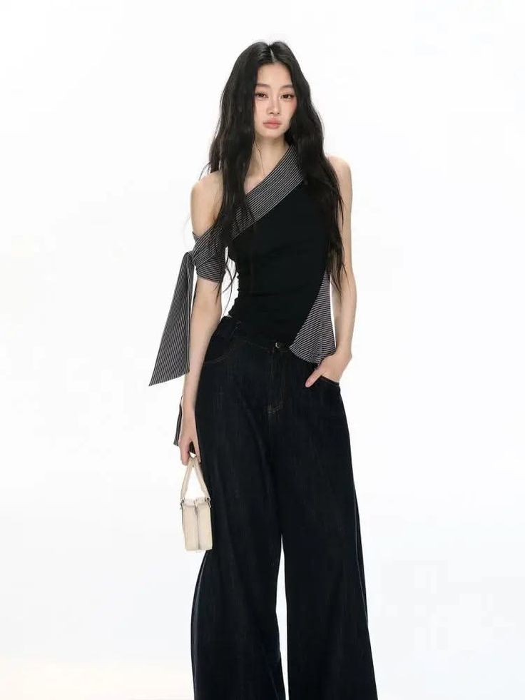 Woman with long black hair wearing an off-shoulder top and wide-leg jeans