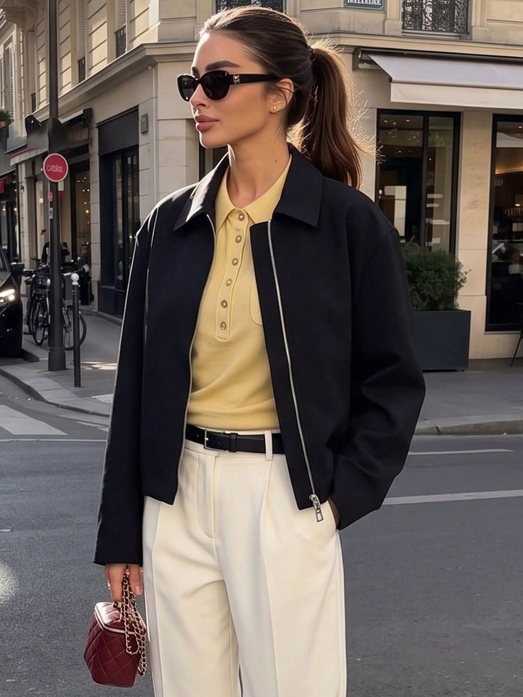 Woman in a black jacket and white pants on a city street
