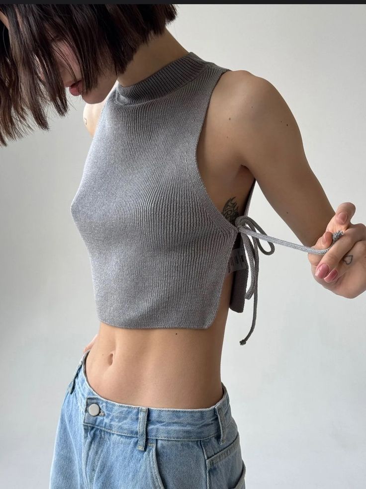 Woman with short hair wearing a grey cropped top and jeans