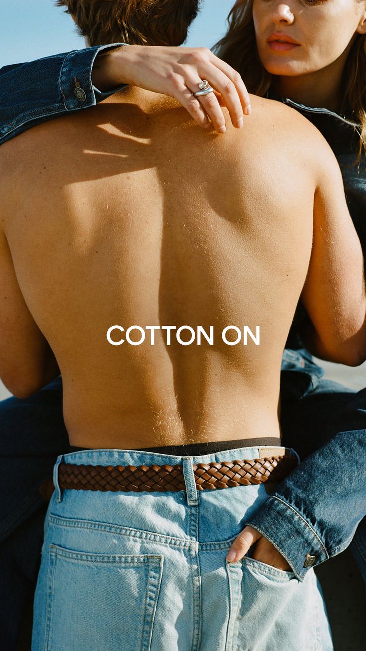 Man's bare back with a woman's arm around him, both wearing denim