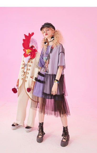 Woman in a purple tulle dress and a person in a rooster costume on a pink background