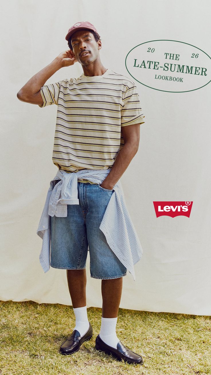Man in a striped t-shirt, denim shorts, and a baseball cap outdoors