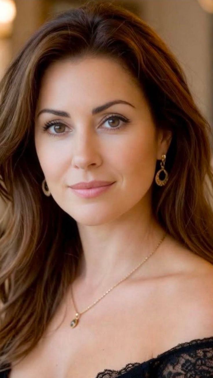 Woman with long brown hair and jewelry looking directly at the viewer