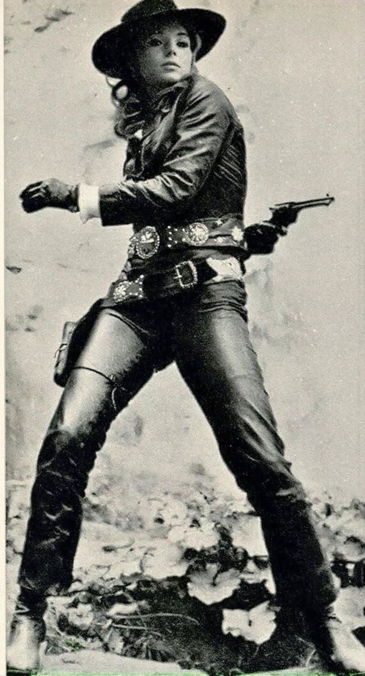 Woman in a cowboy hat and leather outfit with a revolver in a holster