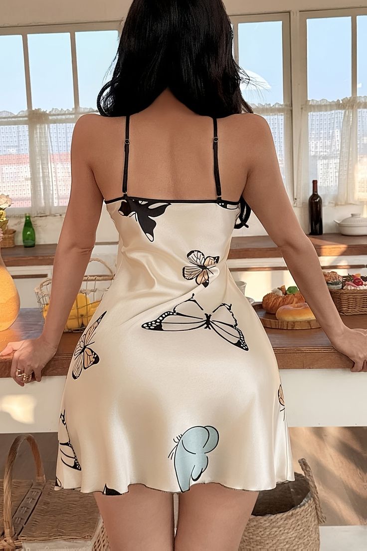 Woman in a short satin dress with butterfly print in a kitchen