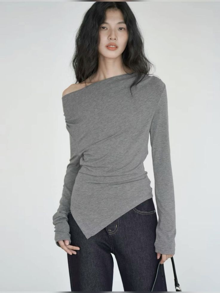 Woman with long dark hair wearing an off-shoulder top and dark jeans