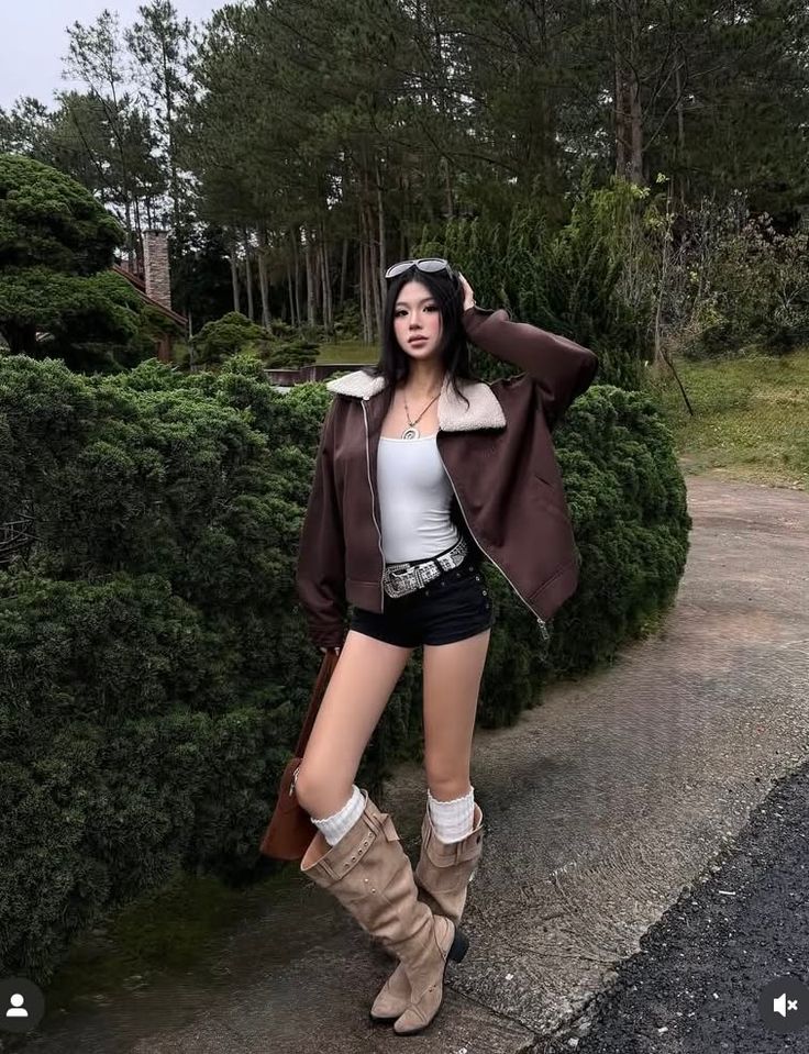 Woman in a brown jacket, short shorts, and tall boots outdoors