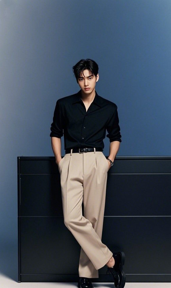 Man in a black shirt and khaki pants posing in a studio