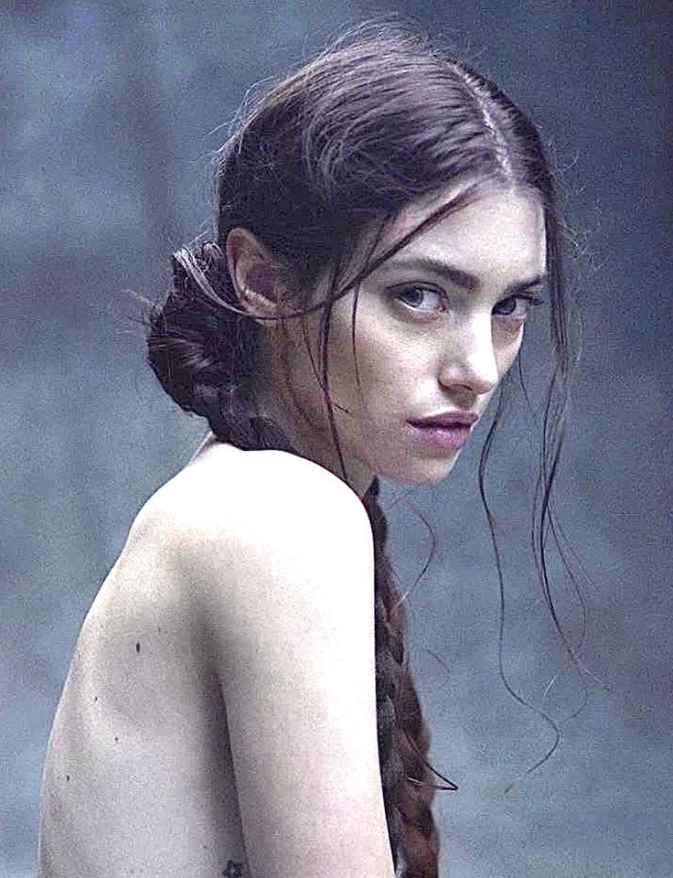 Woman with braided hair looking over her shoulder with exposed skin
