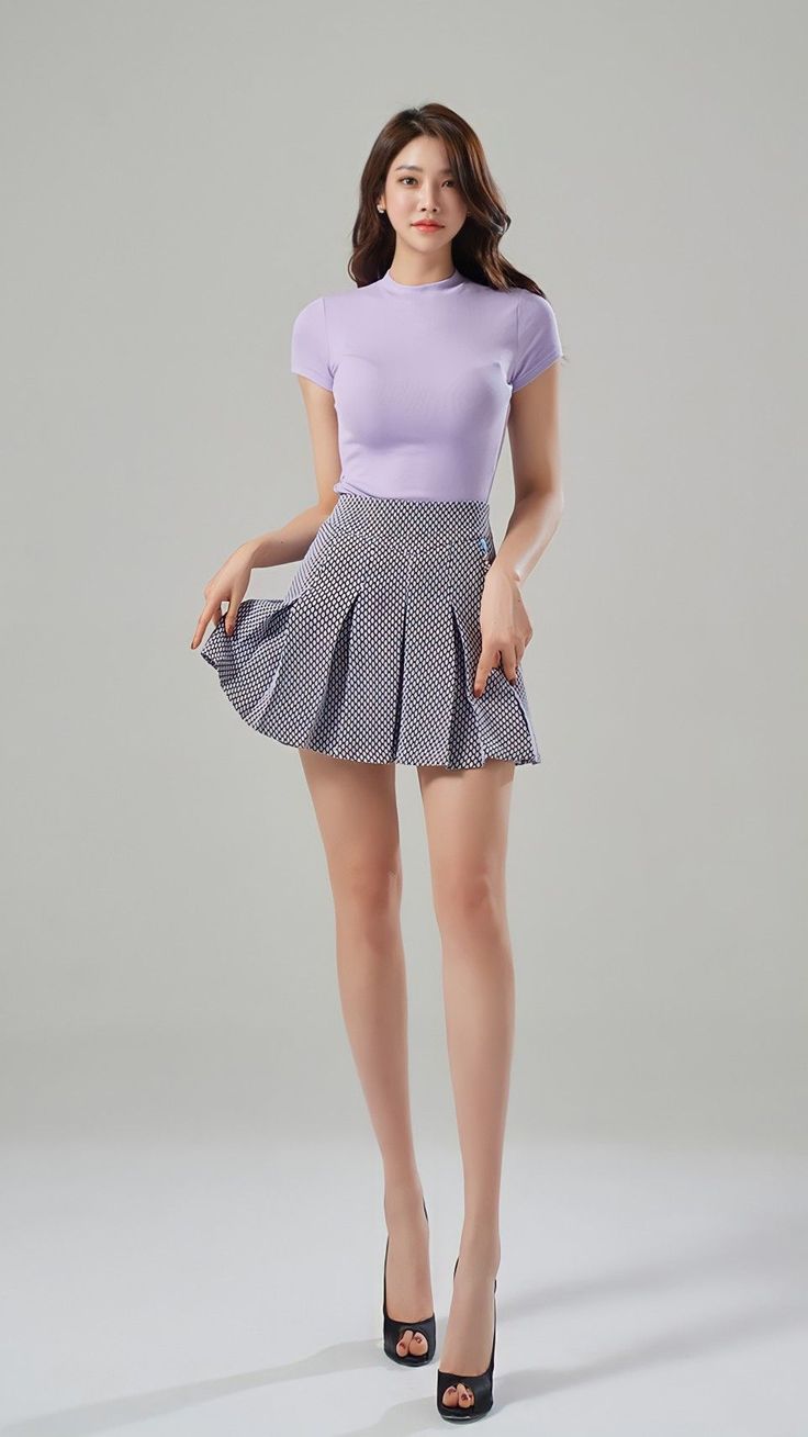 Woman in a lavender top and pleated skirt posing in a studio