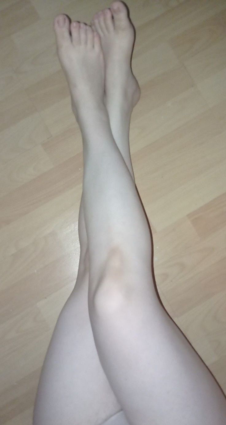 Bare legs crossed at the ankles on a wooden floor