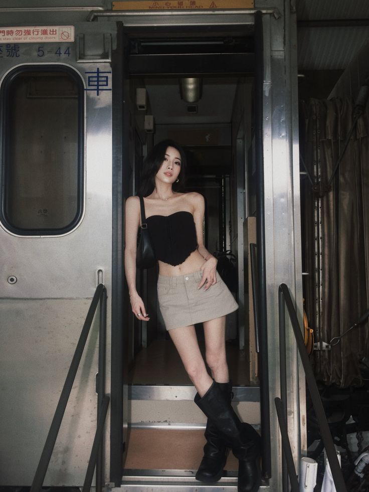 Woman in a black strapless top and mini skirt posing in a train car doorway