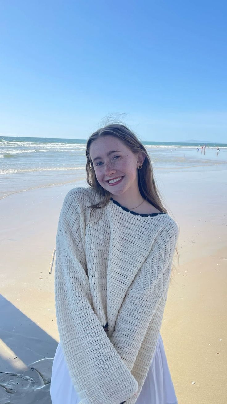 Young woman with long hair and freckles smiling on a sunny beach