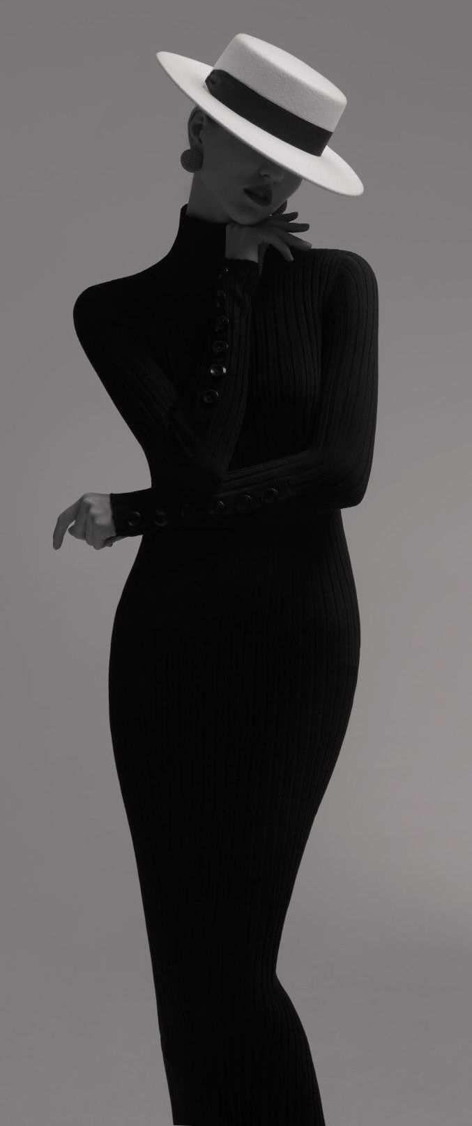 Woman in a black ribbed dress and white hat posing in a studio