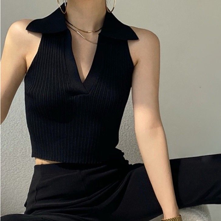 Person wearing a black collared sleeveless top with gold jewelry