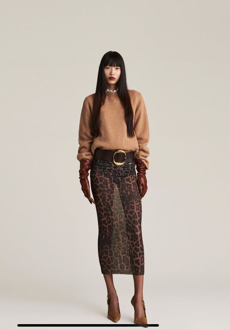 Woman with long black hair wearing a brown sweater and sheer leopard print skirt