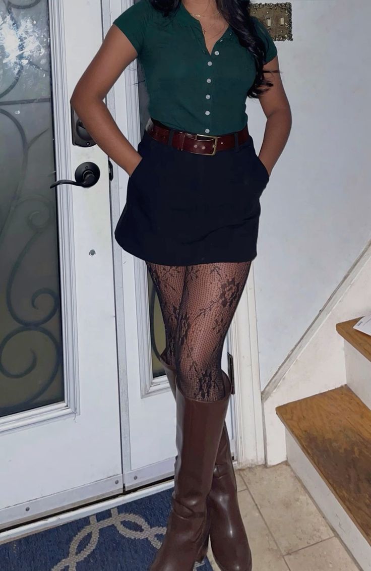 Person in a dark green shirt, black mini skirt, lace tights, and brown boots indoors