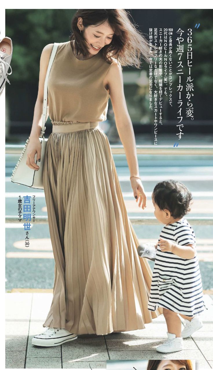 Woman in a pleated skirt and sleeveless top with a child outdoors