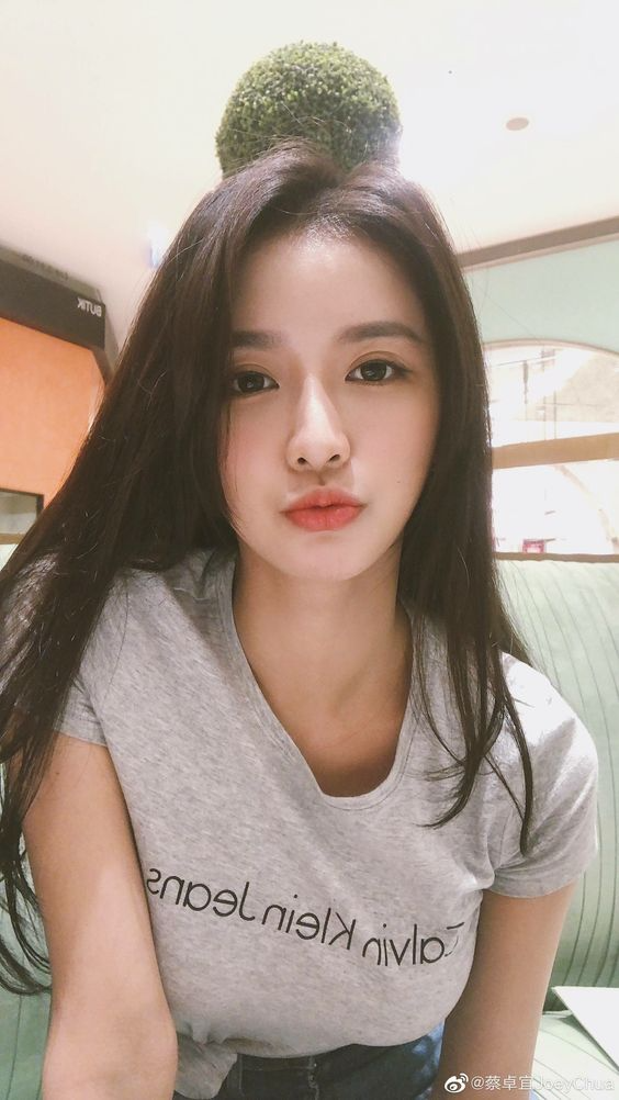 Woman with long dark hair wearing a grey t-shirt indoors