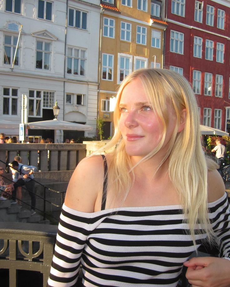 Blonde woman in a striped off-shoulder top outdoors at golden hour