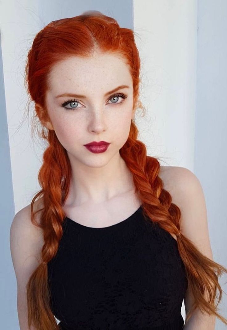 Woman with red braided hair, freckles, and dark lipstick in a black top