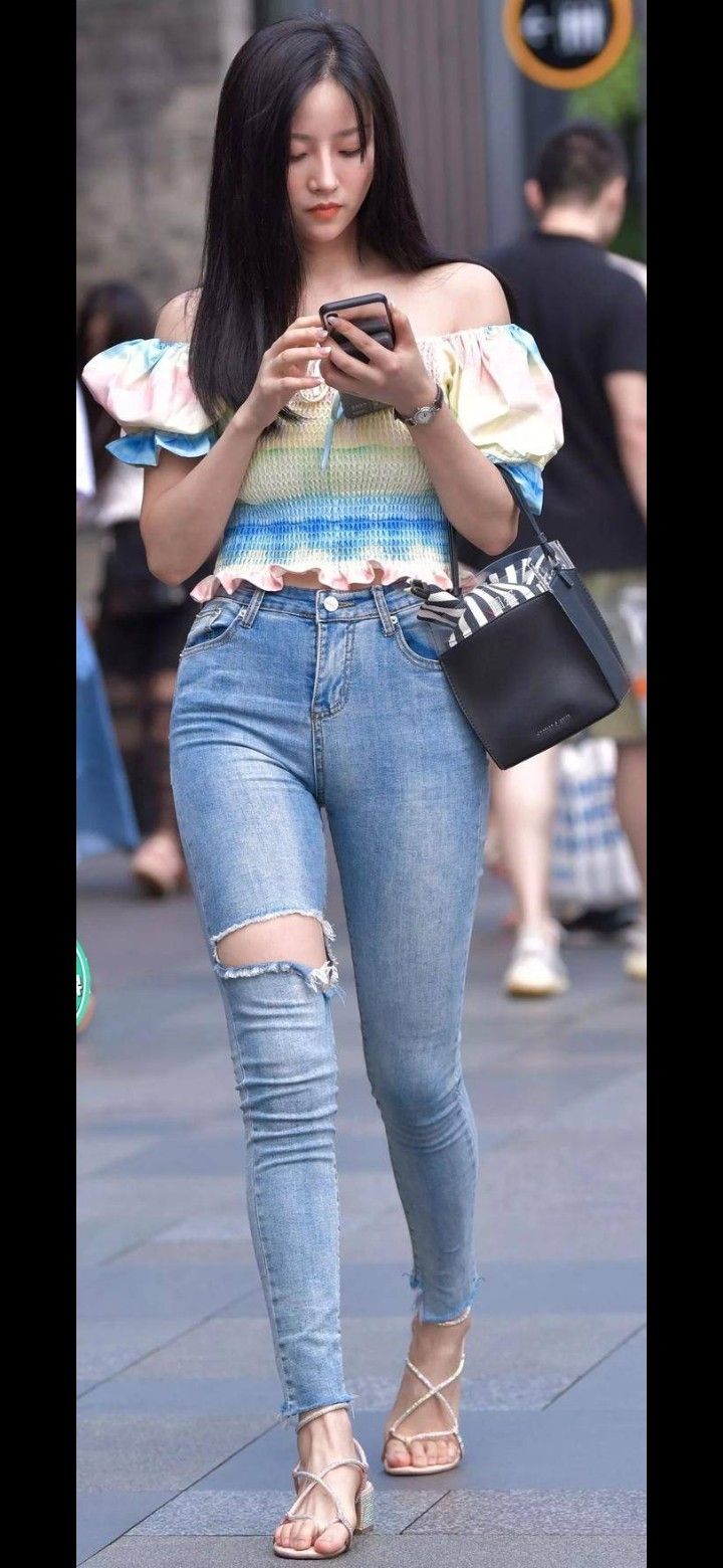 Woman in an off-shoulder top and ripped jeans on a street
