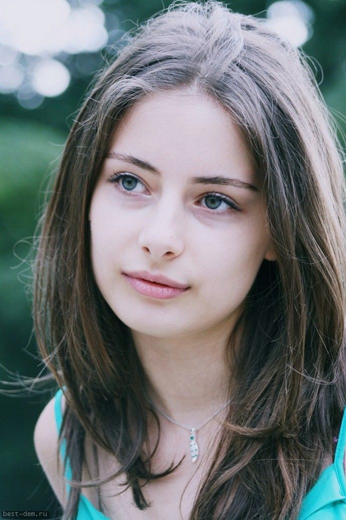 Young woman with long brown hair and blue eyes wearing a silver necklace