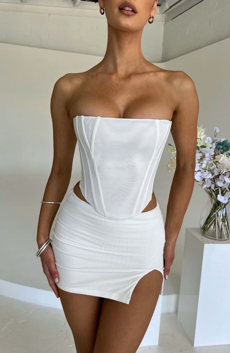 Woman in a white corset top and mini skirt with exposed skin