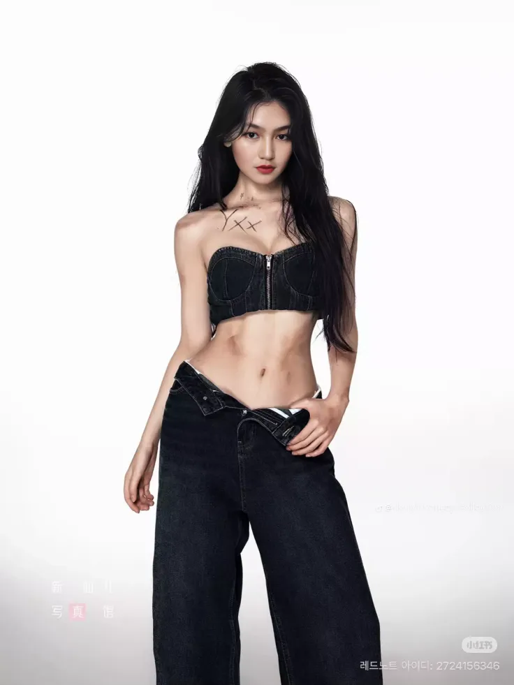 Woman with long black hair wearing a denim top and unbuttoned jeans