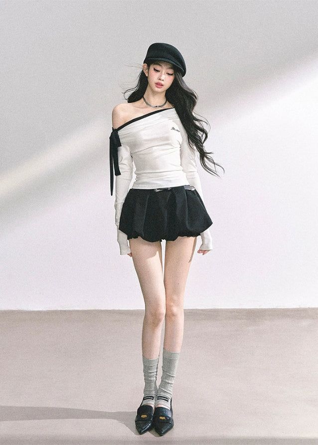 Woman with long black hair wearing a beret, off-shoulder top, and mini skirt
