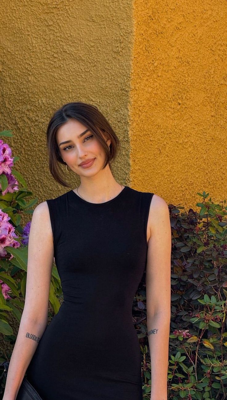 Woman in a black dress with short dark brown hair outdoors