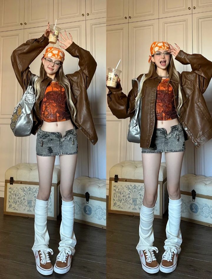 Woman in a brown leather jacket and denim mini skirt posing indoors