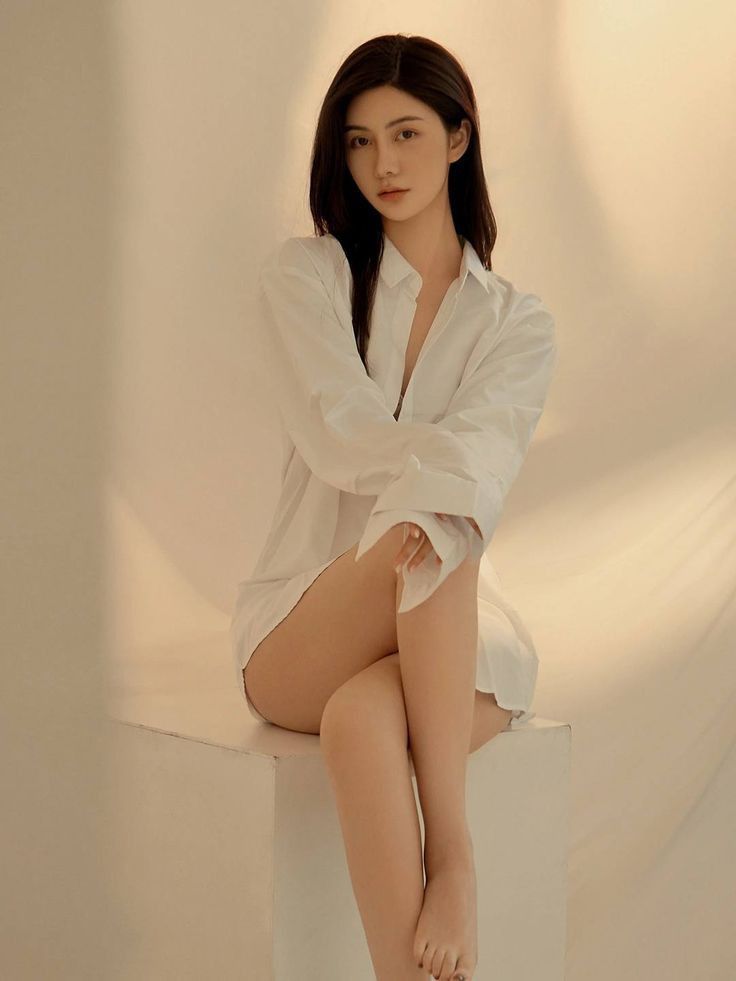 Woman in a white shirt sitting on a white block with soft lighting