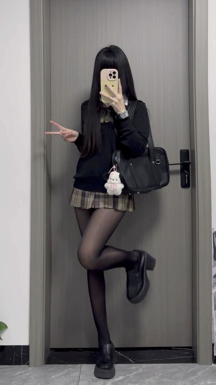 Person in a school uniform taking a mirror selfie with a peace sign