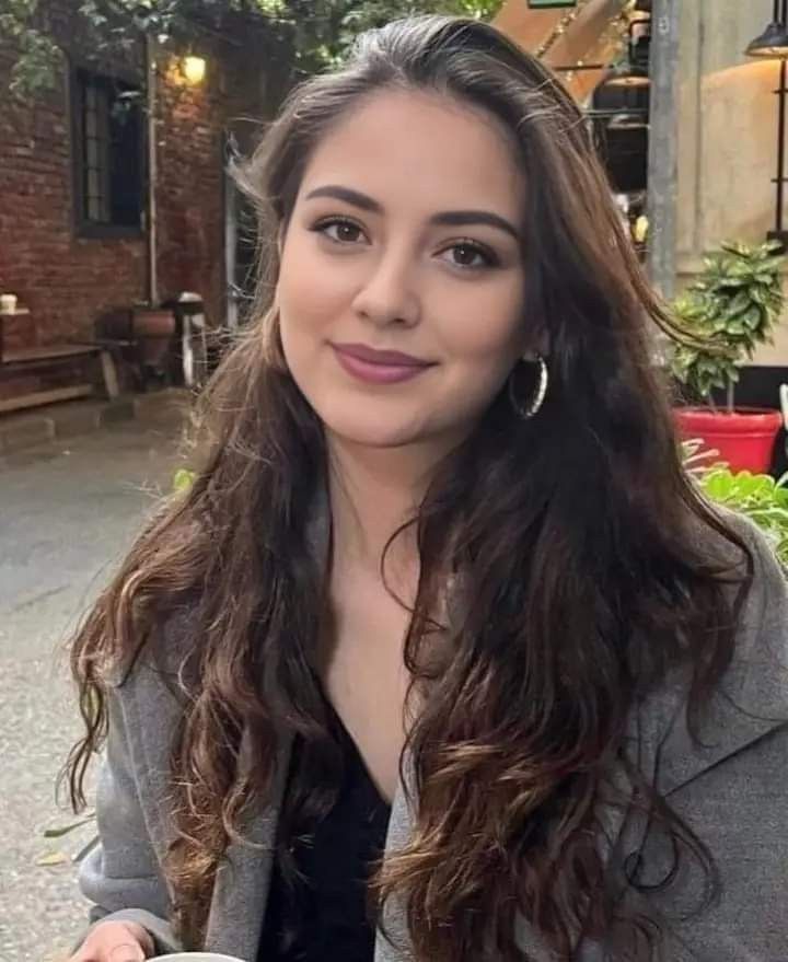 Woman with long brown hair and hoop earrings in an outdoor urban setting