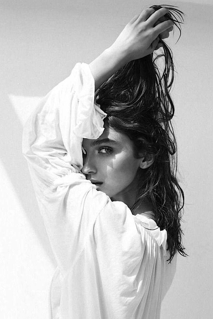 Woman in a white shirt with wet long hair in a dramatic black and white portrait