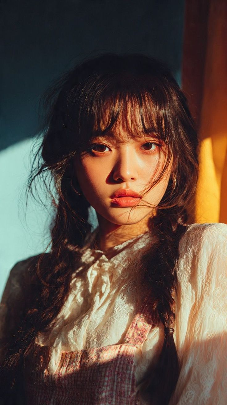Woman with braids and bangs in a lace top with dramatic lighting