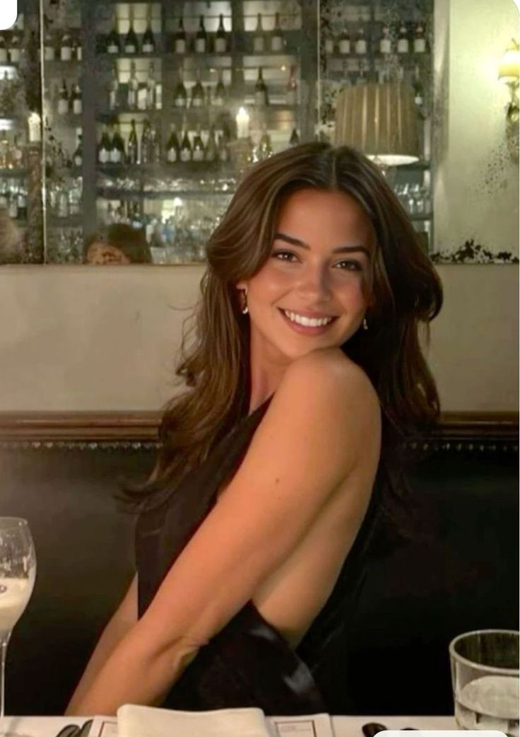 Smiling woman with long hair in a black dress at a restaurant
