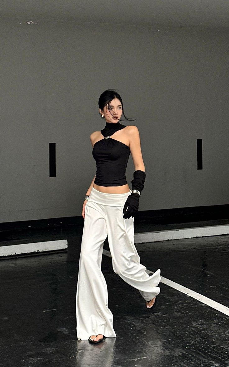 Woman in a black halter top and white wide-leg pants with exposed midriff