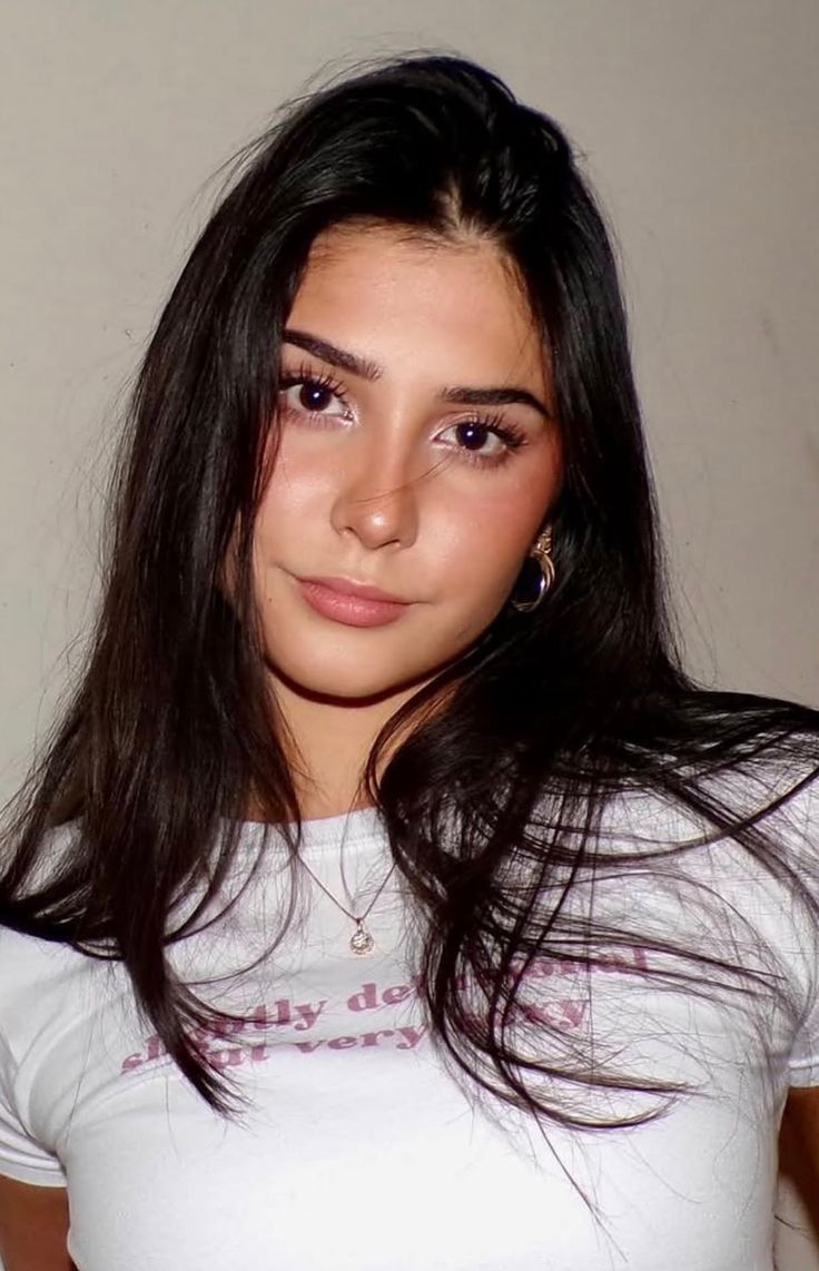 Young woman with long black hair wearing a white t-shirt and hoop earrings