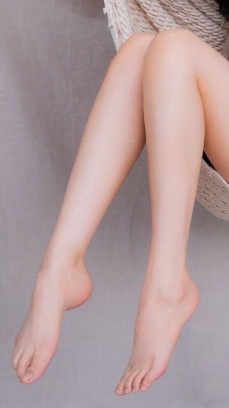 Close up of bare legs and feet against a light background