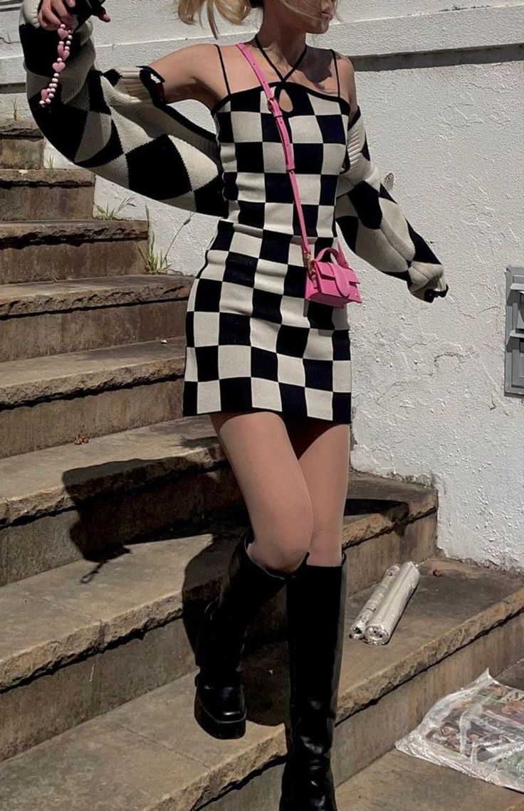Woman in a black and white checkered dress and long boots outdoors