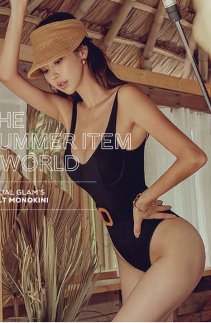 Woman in a black monokini and visor hat posing indoors